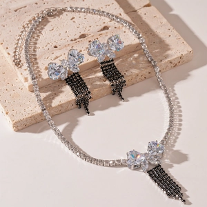 Detailed view of luxury butterfly tassel necklace and earrings set on stone
