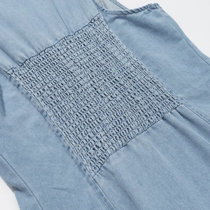 Détail du smock élastique à la taille sur robe en jean bleu clair et texture du tissu