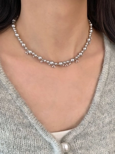 Detail of silver pearl necklace with dainty star charms on a model's neck