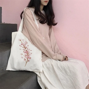Minimalist white canvas tote bag with pink cherry blossom print worn by a model outdoors