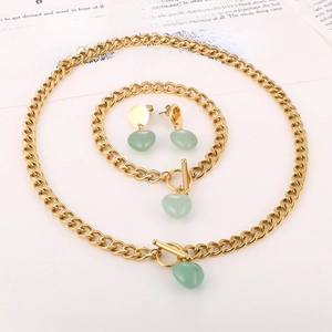 Macro shot of gold OT buckle jewelry set with green stone hearts on book pages