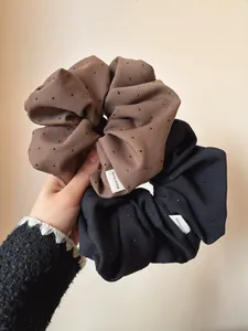 Close-up of handmade scrunchies with star patterns and labels in dark brown and black