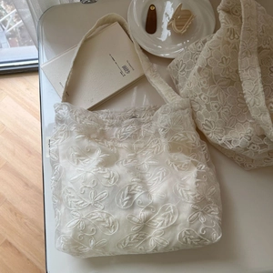 Detailed close-up of white floral lace embroidery on a vintage cotton tote bag