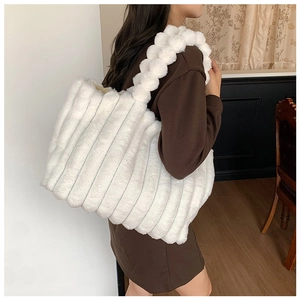 Side view of a white plush striped shoulder bag worn by a model in an indoor setting