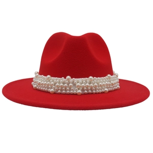 Detailed close-up of luxurious white pearl band on vibrant red wide brim wool fedora hat
