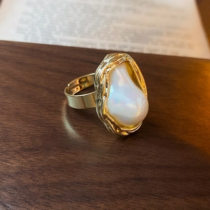 Gros plan d'une grande perle baroque blanche sur une bague ajustable dorée