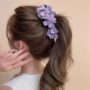 Gros plan d'une élégante pince à cheveux fleurie violette sur la coiffure d'un mannequin