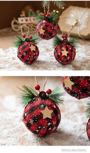 Macro detail of red and black buffalo plaid Christmas ball with pine needles and wood star