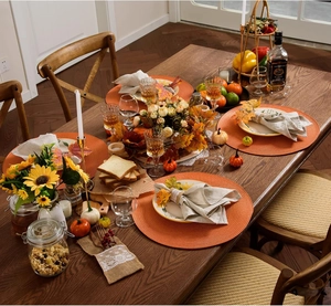 Overhead view of orange woven round placemats in an autumn table setting with pumpkins