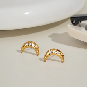 Detail of gold crescent moon stud earrings with three sparkling zircon stones