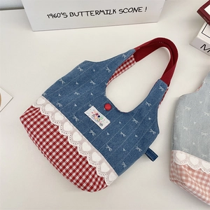 Detail of lace trim and heart embroidery on blue denim and red checkered tote bag