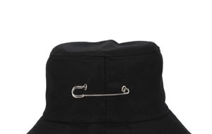 Détail d'un chapeau bob en coton noir avec une grande épingle décorative en métal argenté