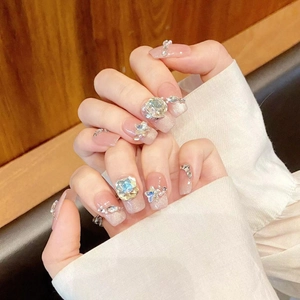 Sparkly pink gradient press-on nails with chunky rhinestones and pearls on hands