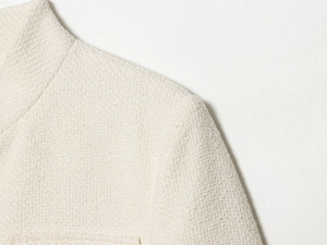 Dettaglio ravvicinato della spalla e del colletto alla coreana in tweed color crema