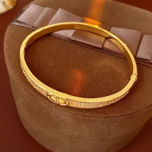 Gold plated cuff bracelet with pave zircons and CD logo clasp on brown velvet