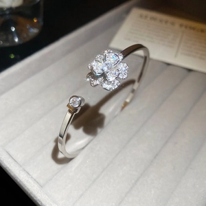 Dettaglio di un bracciale aperto in argento con fiori in zircone su velluto grigio