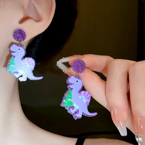 Detail of purple acrylic dinosaur earrings with Christmas tree pattern on model ear