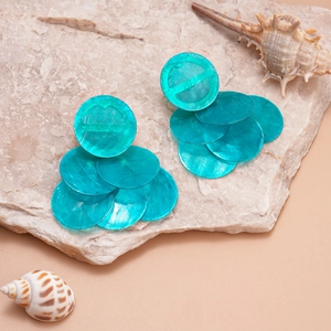 Close-up of turquoise round layered faux shell earrings on a natural stone base