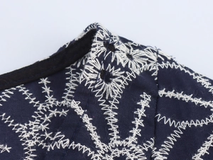 Detailaufnahme der weißen Stickerei auf einem tiefblauen Boho-Kleid für den Urlaub
