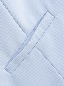 Vue macro du tissu sergé bleu clair et poche passepoilée premium sur le gilet