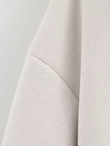 Close-up of shoulder seam detail on light gray sherpa fleece jacket texture