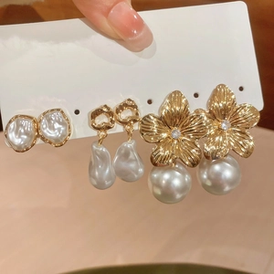 Detail view of pearl earring set with golden heart hooks and flower designs on display card