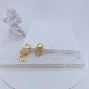 Gold plated cubic zirconia clasp for necklace making on a white textured stone tray