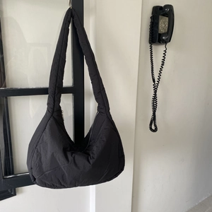 Detail view of the black quilted padded shoulder bag with a secure zipper closure
