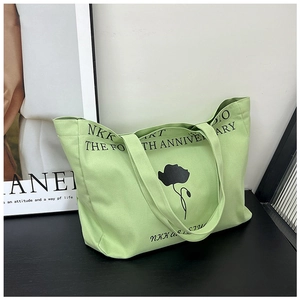 Detail of light green canvas tote bag with black tulip print and artistic NKK lettering