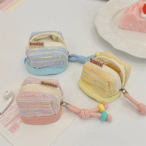 Close-up view of three colorful tweed mini pouches for earphones in pink, blue and yellow.