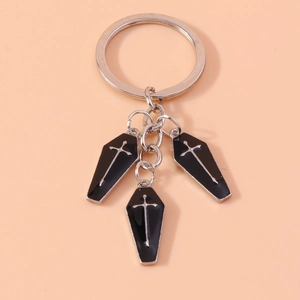 Detail view of gothic keychain with black coffin charms and silver cross on orange background