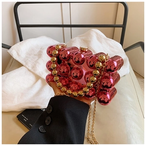Detail of rose red acrylic ball bag with gold beaded handle and metal chain strap