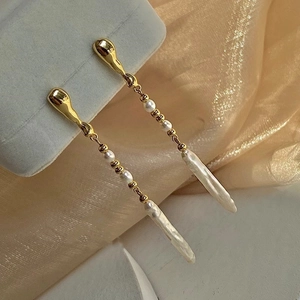 Detailed view of long baroque pearl tassel earrings on champagne silk and jewelry box