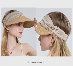 Close-up of woven straw sun hat with champagne satin bow and open top design