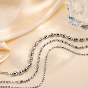 Polished stainless steel oval bead chain bracelet set on champagne satin fabric
