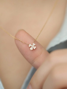 Macro shot of a sparkling four-leaf clover necklace pendant on a gold chain