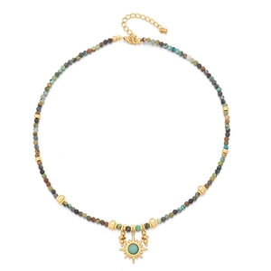 Bohemian beaded necklace with turquoise stones and golden sun pendant on white background