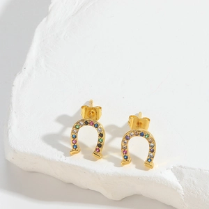 Detailed shot of gold horseshoe stud earrings set with colorful zircon on a stone base