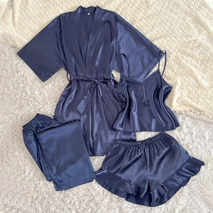 4-piece navy blue satin sleepwear set with robe, camisole, and pants on white faux fur