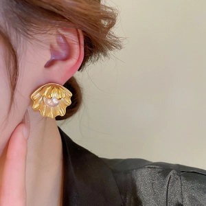 Close-up of vintage gold shell earring with faux pearl on ear for elegant style