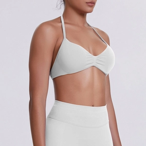 Close-up of white halter sports bra featuring central pleats and premium matte fabric