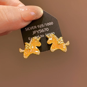 Vue macro de boucles d'oreilles licorne dorées avec cristaux orange et argent 925