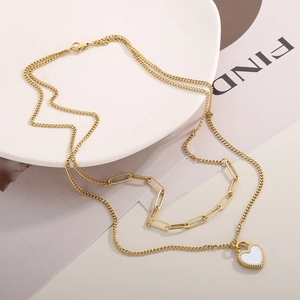 Detail of gold double-layered necklace with white enamel heart pendant and paperclip chain