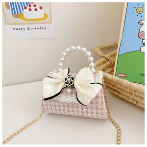 Close-up of pink houndstooth girl's bag with beige bow and pearl handle details