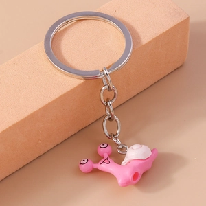 Detailed close-up of a cute pink snail keychain on a natural wooden block accessory