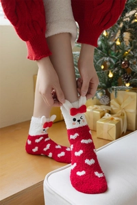 Plush Christmas coral fleece socks with rabbit ears and bows in a cozy home setting