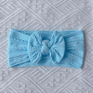 Detail of light blue cable knit baby headband with a large decorative soft bow