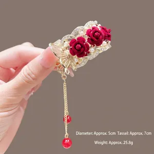 Détail d'une pince à cheveux rose rouge avec perles blanches et long gland doré de 5 cm