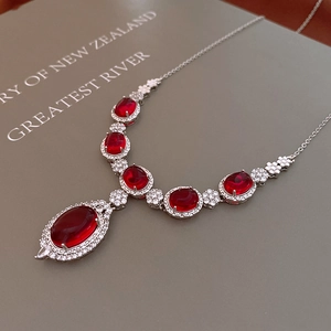 Macro shot of silver chain with red oval gemstone pendants and sparkling zircons