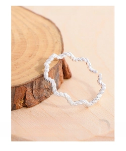 Macro detail of S925 sterling silver twisted wave ring on a warm wood background
